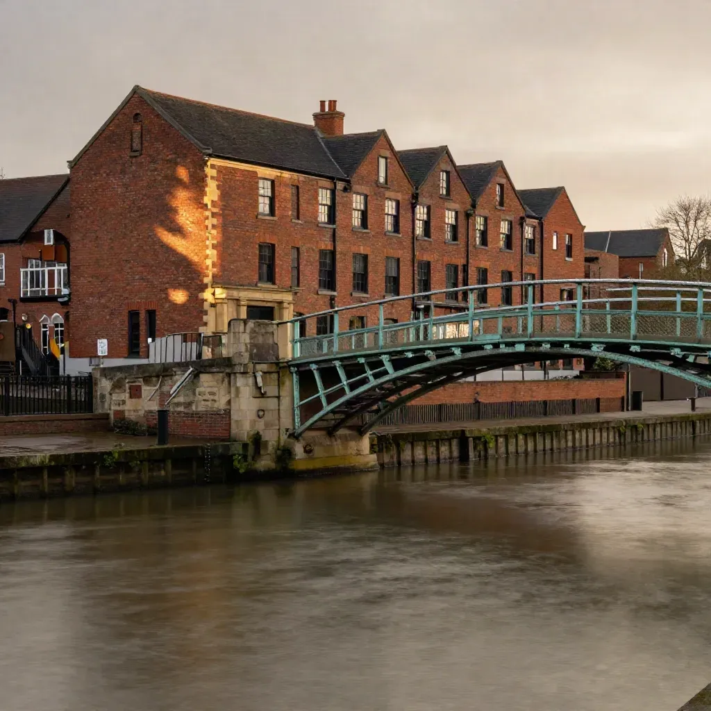 Quiet Midlands canal scene with red-brick civic buildings and an iron bridge at dusk.